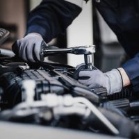 Professional mechanic working on the engine of the car in the garage. Car repair service. The concept of checking the readiness of the car before leaving.